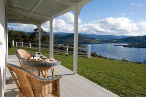 a table and chairs on a porch with a view of a lake at Villa Talia Tasmania in Wattle Grove