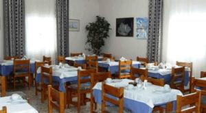 uma sala de jantar com mesas e cadeiras azuis e brancas em Babis Hotel em Karterados