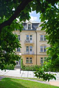 a large yellow building with a balcony at Villa Dagmar in Luhačovice