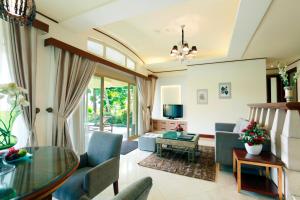 een woonkamer met een glazen tafel en blauwe stoelen bij R Hotel Rancamaya in Bogor