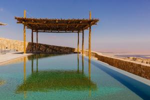 a pool of water with a wooden structure over it at Six Senses Shaharut in Shaharut