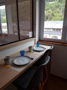 une table avec deux assiettes, deux chaises et une fenêtre dans l'établissement STUDIO 21 M2 TOUT EQUIPE, à Modane