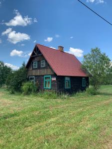 an old house with a red roof in a field at DOMY na GÓRCE in Narty