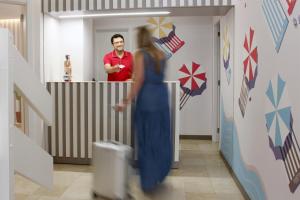 a man standing behind a counter with a woman in a blue dress at Apartamentos Ribera in Benidorm