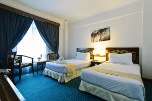 a hotel room with two beds and a window at Hotel Seri Malaysia Melaka in Melaka