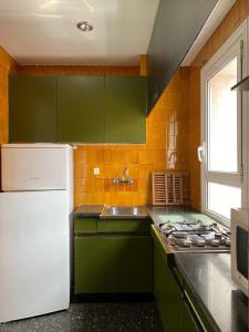 a kitchen with green cabinets and a white refrigerator at Mediterranean apartment in Lloret de Mar next to the Sea in Lloret de Mar