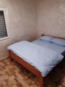 Un dormitorio con una cama con sábanas azules y una ventana. en Apartmani Kosmac, en Budva