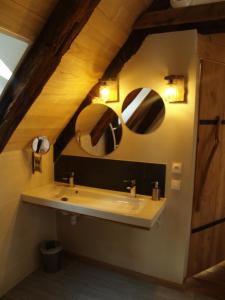 La salle de bains est pourvue d'un lavabo et de 2 miroirs sur le mur. dans l'établissement Gîte Nature, à Vitrac-sur-Montane