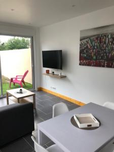 ein Wohnzimmer mit einem Tisch und einem TV in der Unterkunft Appartement avec jardin in Isbergues
