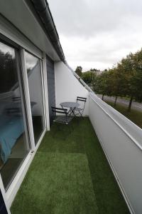 un patio con una mesa en un balcón con césped en Les Platanes en Saint-Lô