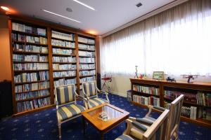 a library with two chairs and a table and books at Hotel Marital Sousei Kurume in Kurume