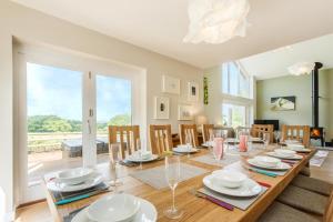 een eetkamer met een grote houten tafel en stoelen bij Blackdown Views - New 6 Bedroom Eco House in Dunkeswell