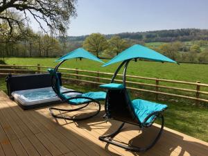 twee stoelen en een bed op een terras met een veld bij Blackdown Views - New 6 Bedroom Eco House in Dunkeswell