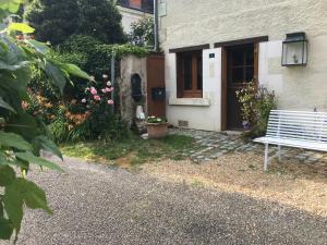 een bankje buiten een huis met bloemen bij LA MAISON DE LUCIE in Veuil