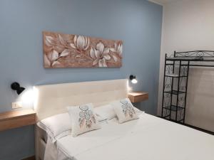- une chambre dotée d'un lit blanc avec des oreillers et un tableau dans l'établissement Il Tucano - Taormina, à Taormine