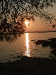 a sunset over a body of water with the sun setting at Apartments Tamara in Sukošan