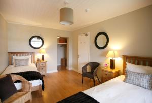 a bedroom with two beds and a chair and two mirrors at Margaret's Cottage B&B in Ardglass