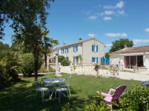 einen Garten mit Stühlen, einem Tisch und einem Haus in der Unterkunft Le Clos des Palmiers in Saint-ouen-dʼAunis