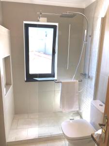 a bathroom with a shower and a toilet and a window at The Yellow House in Paul do Mar