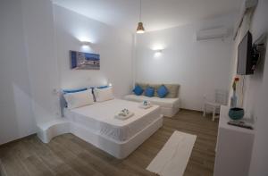 a white room with a bed and a couch at studio lefkes kea in Vourkari