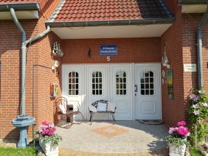 a brick house with a white door and a chair at Pension Nordseebriese in Dornum