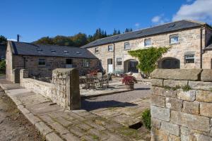 an old stone building with a table and chairs in front of it at Cragend Grange in Rothbury