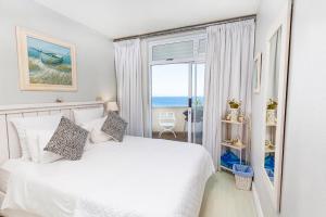 a bedroom with a white bed and a large window at 43 Sea Lodge - by Stay in Umhlanga in Durban