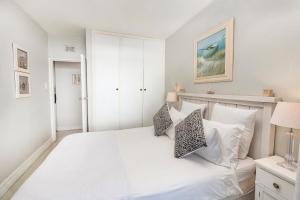a white bedroom with a large white bed with pillows at 43 Sea Lodge - by Stay in Umhlanga in Durban +26 photos