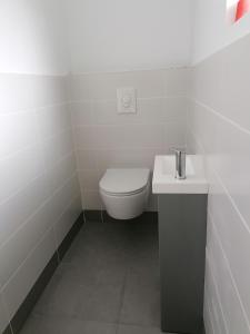 La salle de bains blanche est pourvue de toilettes et d'un lavabo. dans l'établissement Les gîtes aux portes de Saint-Quay-Portrieux, à Plourhan