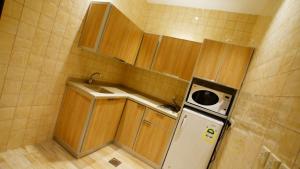 a small kitchen with wooden cabinets and a refrigerator at Al Muhaidb Residence Sudair - Economic in Ḩawţat Sudayr +8 photos