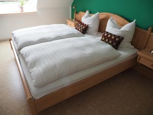 ein großes Bett mit weißer Bettwäsche und Kissen darauf in der Unterkunft Ferienhof Meyer in Nahrendorf