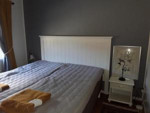 Un dormitorio con una cama blanca con una manta. en The Cottage Badelunda, en Västerås