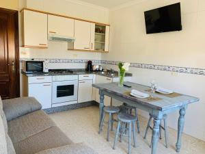 a kitchen with a table with chairs and a tv at Pensión San Antón in Sanxenxo