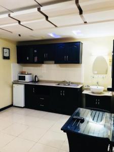 una cocina con armarios negros y fregadero blanco en Urban Rose Hotel & Apartments, en Dar es Salaam