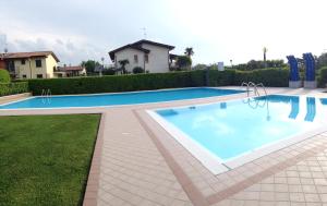 a large swimming pool with blue water in a yard at Appartamento di Charme Suite Sole in Lazise