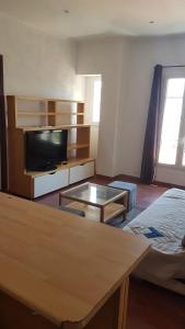 a living room with a tv and a table at Appartement Buenos Aires in Nice