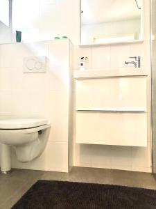biała łazienka z toaletą i umywalką w obiekcie Tuinkamer "de Duiventil" aan de rand van de Posbank w mieście Velp