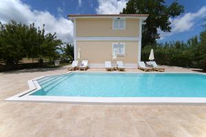 a villa with a swimming pool in front of a house at Mirsini Studios & Apartments in Laganas