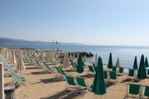 a row of lawn chairs and umbrellas on a beach at Residence Aurora in Albenga