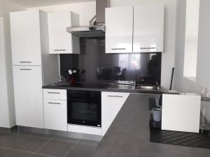 a kitchen with white cabinets and a black stove at Le coin des Oliviers in Puget-sur Argens