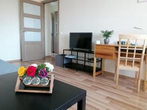 a living room with a table with flowers and a television at Apartment Anna in Saldus