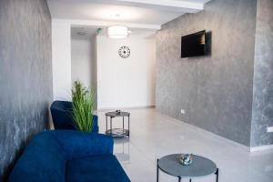Hotel Premium في إيفوري نورد: غرفة معيشة مع أريكة زرقاء وتلفزيون