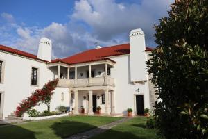 une grande maison blanche avec un toit rouge dans l'établissement Quinta do Regalo, à Coimbra