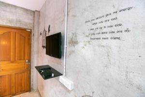 een muur met een tv en schrijven op de muur bij OYO 945 The Rome Resort in Pran Buri