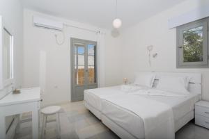 una camera bianca con letto bianco e scrivania di Heart of Paros Apartments a Kampos Paros