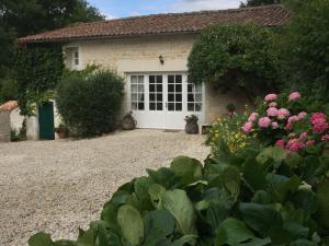 una casa con una puerta blanca y algunas flores en Gîte Le Dolmen, Cognac, en Julienne