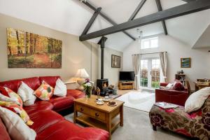a living room with a red couch and a table at Criddlestyle Cottage - 5 bedroom New Forest Holiday Home in Fordingbridge