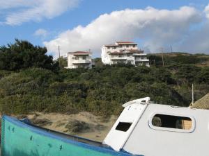 a boat in front of two houses on a hill at Nora Norita in Batsi