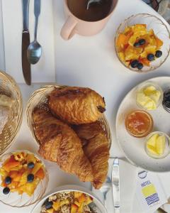 a table with plates of breakfast foods and a croissant at Hôtel Le Sud in Juan-les-Pins