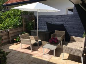 een patio met 2 stoelen en een parasol bij Annadora Beach House - Free Parking in Zandvoort